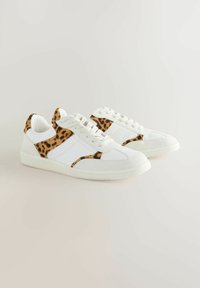 White sneakers with leopard print accents on the sides, featuring a smooth texture, round toe, and flat rubber sole. Laces in front.