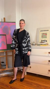 Kimono-stil kratka jopica s črno-belimi vzorci, kombinirana s črnim zgornjim delom in širokimi črnimi hlačami. Obleko dopolnijo črne čevlje s kvadratnim nosom.