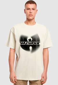 Kreminė trumpa rankovė t-maišis iš medvilnės, su dideliu juodu ir pilku Wu-Tang logotipo grafinį, laisva forma ir apvaliu iškirpimu.