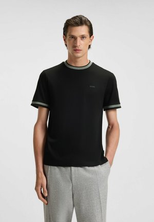 T-shirt nera a maniche corte, con dettagli verdi sul colletto e sulle maniche. Design minimalista con un piccolo logo sul davanti.