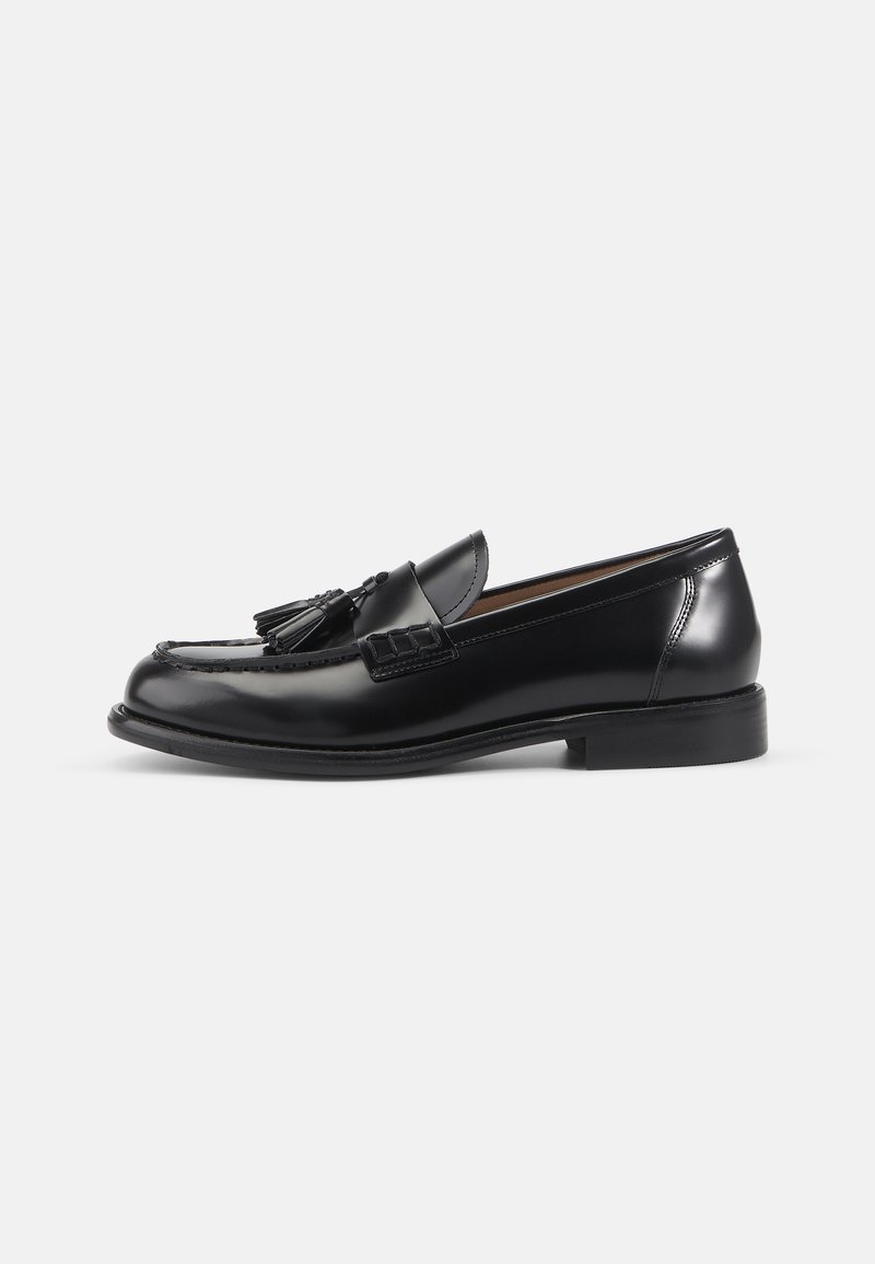 Zwarte gepatineerde leren loafers met een ronde neus, decoratieve kwastjes, gegraveerde details en een lage gestapelde hak. Glad, glanzend oppervlak.