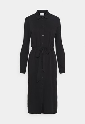 Robe chemise mi-longue noire à manches longues avec col, boutons sur le devant et ceinture nouée à la taille, présentée sur un fond blanc uni.