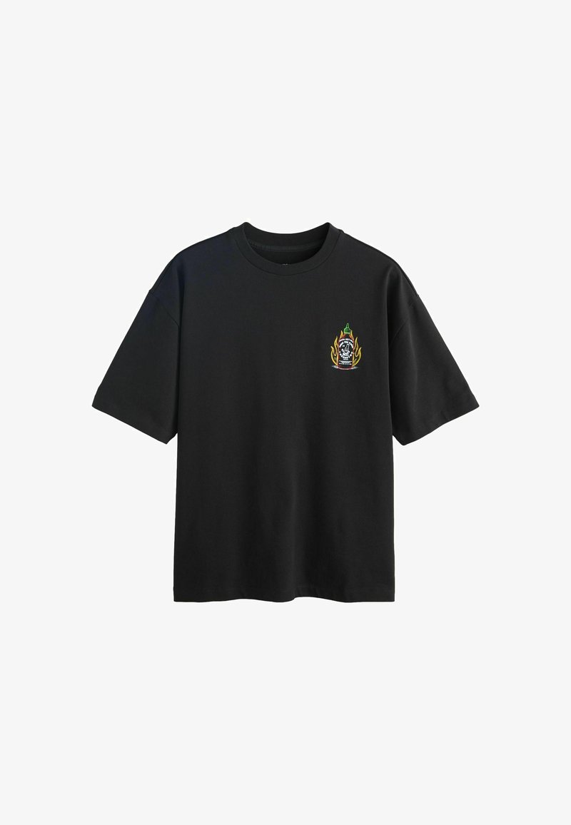 T-shirt noir à manches courtes avec un petit graphisme représentant une bouteille de sauce piquante en flammes sur le côté gauche de la poitrine.