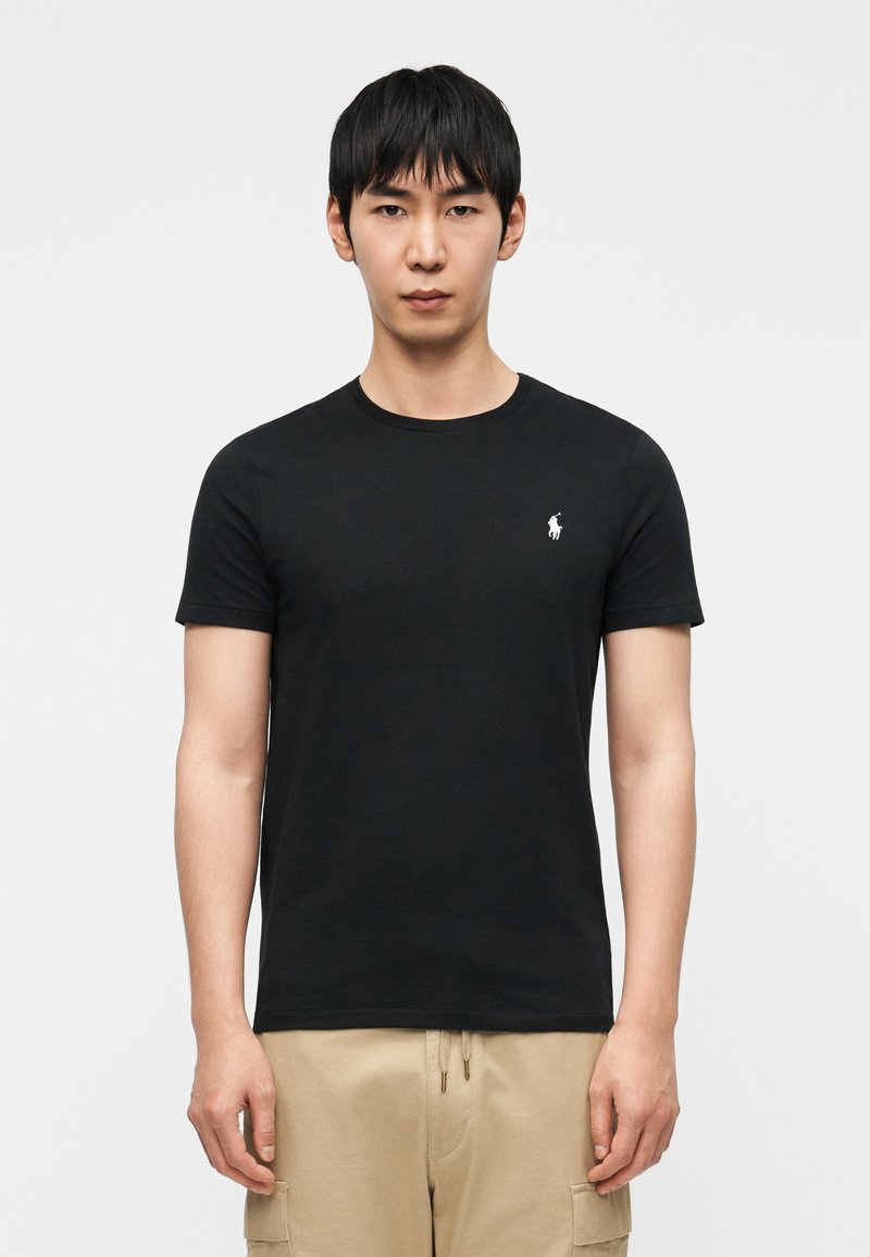 Μαύρο βαμβακερό μπλουζάκι με στρογγυλή λαιμόκοψ η και κοντά μανίκια· διαθέτει μικρό λευκό λογότυπο στο αριστερό στήθος· ομαλή υφή.