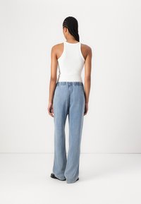 Hvit ribbestrikket singlet kombinert med lyseblå, vide jeans med elastisk midje. Glatt stoff og avslappet passform.