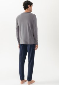 Grijs langemouwen shirt met een ronde kraag, gecombineerd met marineblauwe broek. De stof lijkt zacht en casual, met een ontspannen pasvorm.