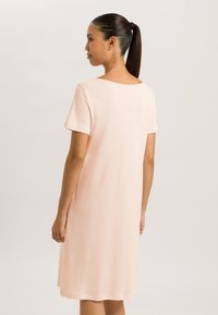 Pink short-sleeve dress with a loose fit, crew neckline, and smooth texture. The hem falls just above the knees, showcasing a simple design.
