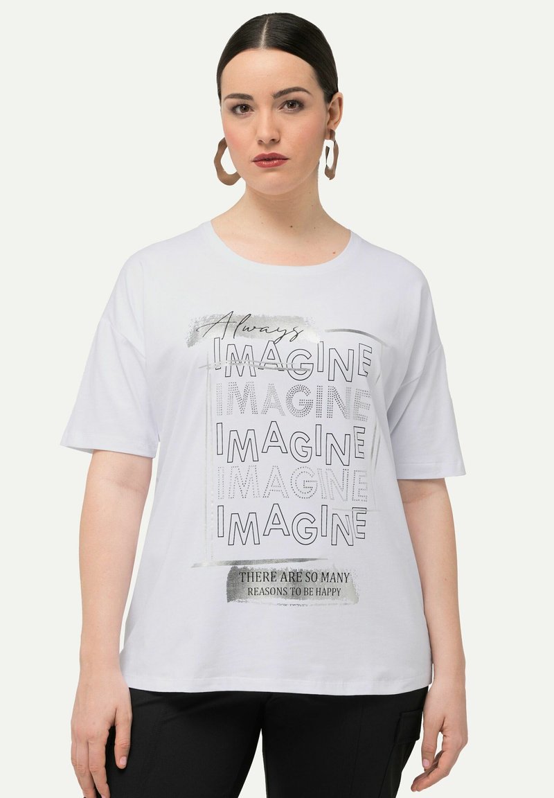 Hvid t-shirt med korte ærmer med sort tekst: "Always IMAGINE" og "DER ER SÅ MANGE GRUNDE TIL AT VÆRE LYKKELIG." Casual pasform, glat tekstur.