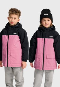 Deux enfants portent des vestes à capuche. Les vestes présentent une partie supérieure noire et une partie inférieure rose, fabriquées dans un matériau lisse et léger.