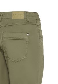 Jean vert olive montrant la poche arrière avec couture et étiquette de marque en cuir marron clair "PULZ JEANS" sur la ceinture.