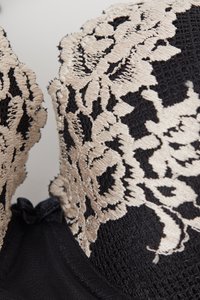 Černá podprsenka s béžovou květinovou krajkovou aplikací, vroubkovanými okraji, texturovanou síťovinou a středovým mašlí na předním pásku.