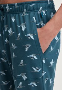 Teal shorts met een herhalend patroon van vliegende ganzen, voorzien van een elastische tailleband en zijzakken. Zachte, lichte stof met een gladde textuur.
