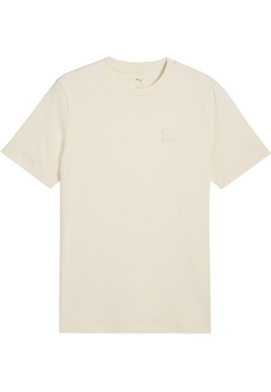 T-shirt de couleur crème en coton doux, avec des manches courtes et un petit écusson logo carré sur la poitrine gauche.