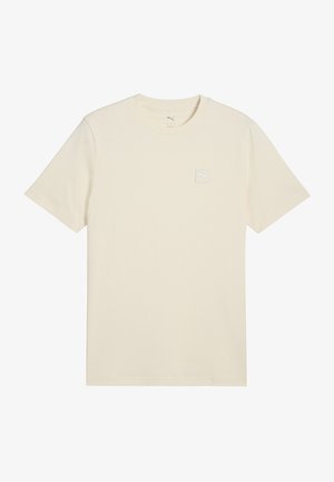 Valkoinen t-paita, joka on valmistettu pehmeästä puuvillasta, jossa on lyhyet hihat ja pieni neliönmuotoinen logo-tarra vasemmalla rinnalla.