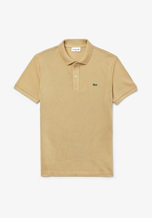 Polo beige con tessuto testurizzato, colletto a tre bottoni e logo Lacoste ricamato sul lato sinistro del petto. Maniche corte.