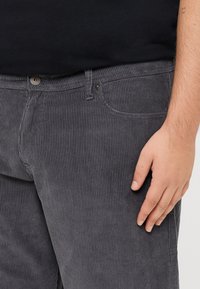 Grijze corduroy broek met verticale ribbeltextuur, vijf zakken, metalen knoopsluiting en subtiele stiksels.