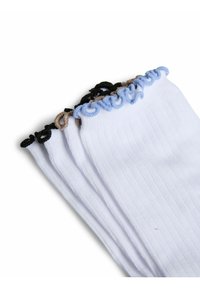 Pile de chaussettes blanches côtelées avec des bords à volants en noir, marron et bleu sur fond blanc.