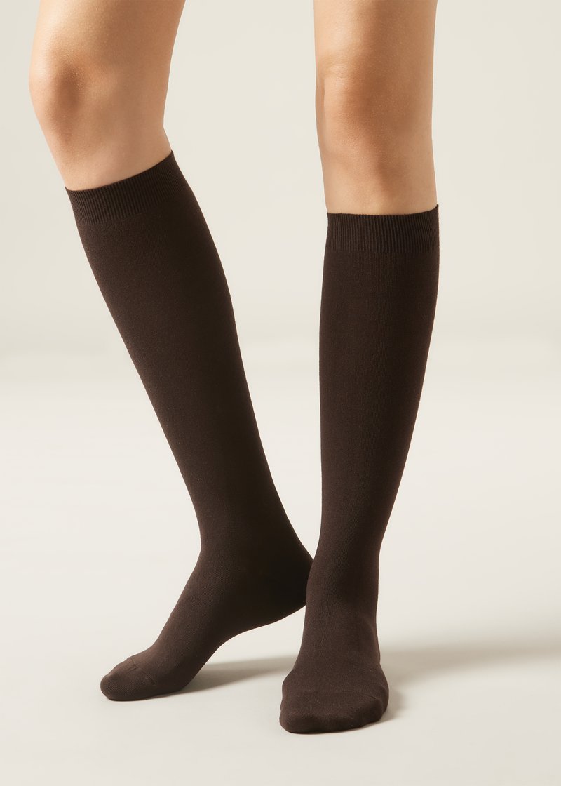 Kniestrümpfe aus einem festen, dunkelbraunen Stoff, die eine glatte Textur und ein geripptes Oberband aufweisen. Geeignet für verschiedene Outfits.