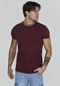 Bordowa koszulka z krótkim rękawem z żebrowanym okrągłym dekoltem i wytłoczonym logo "SIKSILK". Zaprojektowana w dopasowanym kroju, wykonana z miękkiej bawełny.