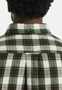 Geruite shirt met bruine, groene en witte kleuren, voorzien van een button-down kraag en plooidetail aan de achterkant. Zachte, gestructureerde stof.