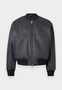 Μαύρο καπιτονέ bomber μπουφάν με φερμουάρ μπροστά, ριμπ μανσέτες και τελείωμα, και διακριτικό ανάγλυφο κείμενο «JORDAN» στο στήθος.