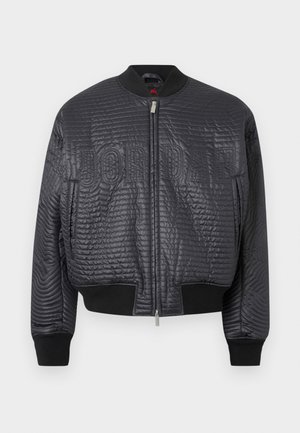 Μαύρο καπιτονέ bomber μπουφάν με φερμουάρ μπροστά, ριμπ μανσέτες και τελείωμα, και διακριτικό ανάγλυφο κείμενο «JORDAN» στο στήθος.