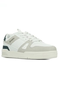 Sneaker bianca e grigia chiara realizzata in pelle e camoscio, con colletto imbottito, suola intermedia testurizzata e dettagli in un verde scuro a contrasto.