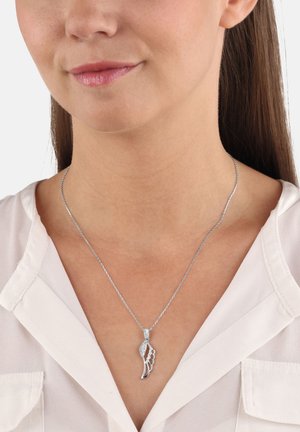 Collana d'argento con pendente a forma di ala decorato con pietre brillanti, su una delicata catena sopra una camicia colletto.