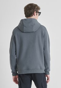 Felpa grigia con cappuccio ampio, polsini e orlo ribattuti. Realizzata in materiale morbido, con una texture liscia e una vestibilità comoda.