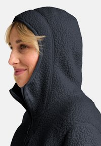 Schwarzer Fleece-Hoodie mit strukturierten Oberflächen, hohem Kragen und angenommener Kapuze. Verfügt über einen Reißverschluss und ein enganliegendes Design.