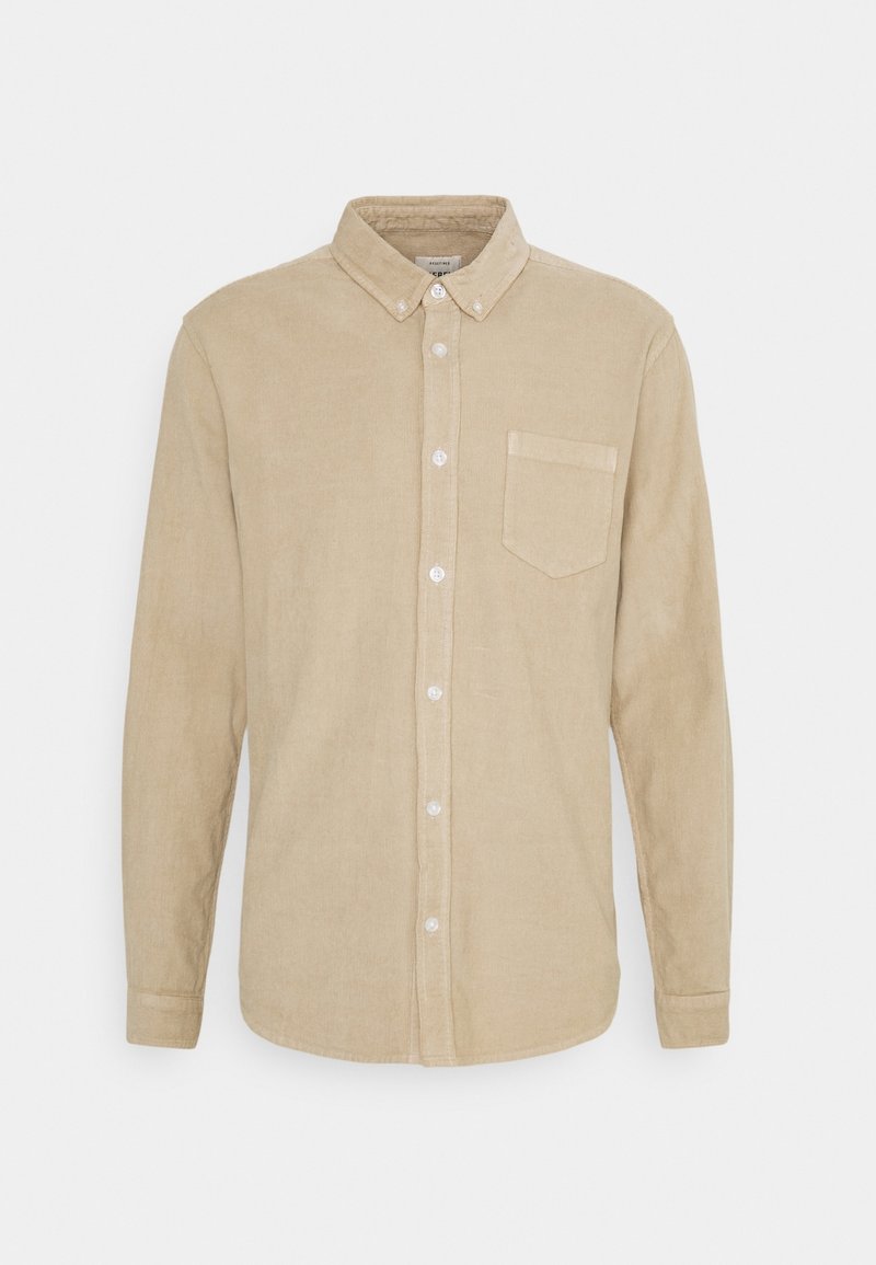 Chemise beige en velours côtelé à manches longues, col boutonné, poche avant sur le côté gauche et boutons blancs au centre.