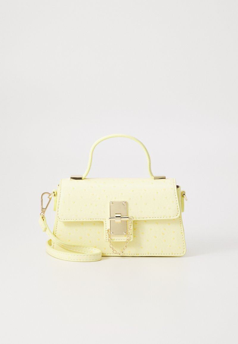 Sac à main en simili cuir jaune avec une surface texturée, des accessoires en métal doré, une poignée supérieure et une bandoulière amovible. Il est doté d'une fermeture à fermoir.