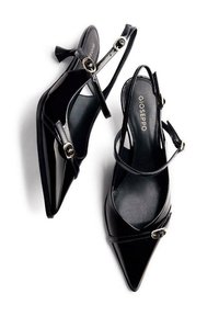Scarpe con tacco alto in vernice nera, con punta appuntita, cinturini alla caviglia e dettagli in oro. Texture liscia, design moderno.