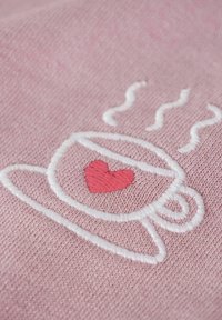 Wyszywany wzór białej filiżanki na różowym tle, z małym czerwonym serduszkiem i liniami pary unoszącymi się nad filiżanką. Teksturowane wykończenie.