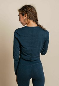 Námornícky modré tričko s dlhým rukávom, okrúhlym výstrihom a skráteným strihom, so hladkou textúrou a jemnými detailmi švov.