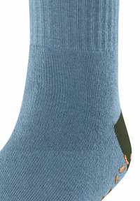 Chaussette bleu clair avec texture côtelée et talon vert. Présente des taches orange près des orteils, fabriquée à partir d'un matériau doux et extensible.