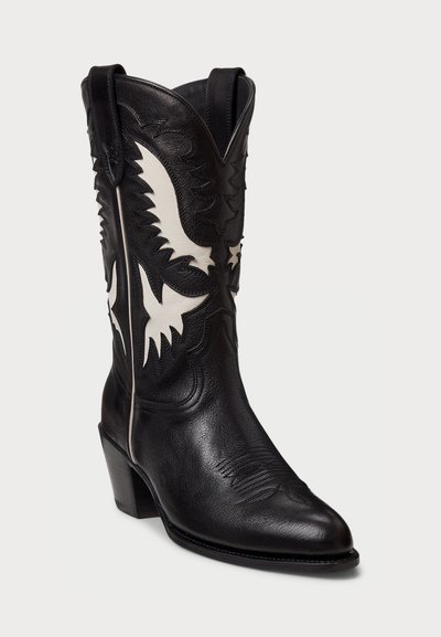Mustan nahast cowboy-saapa, millel on valge tikandiga kotka kujutis, terav nina ja kitsenev konts. Dekoratiivne õmblemine varre ääres.