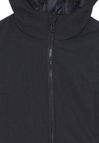 Giacca nera con cappuccio caratterizzata da una texture liscia, zip frontale e due tasche laterali con dettagli di cuciture circolari.