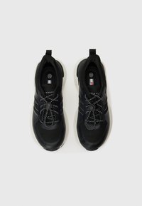 Baskets de sport noires avec mailles texturées et panneaux synthétiques lisses. Dotées de lacets élastiques et d'une semelle rembourrée. Design minimaliste.