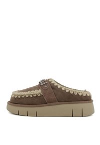 Scarpa slip-on in suede marrone con un accento intrecciato beige e dettaglio in fibbia argentata, dotata di una suola beige spessa e texture.