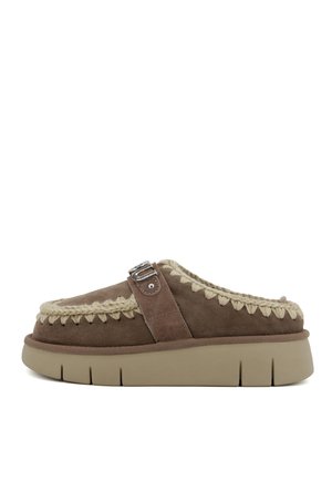 Scarpa slip-on in suede marrone con un accento intrecciato beige e dettaglio in fibbia argentata, dotata di una suola beige spessa e texture.