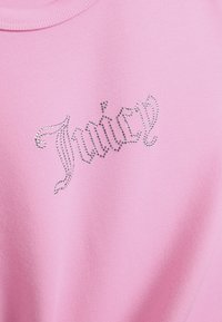 Ροζ φούτερ με διακοσμητικό σχέδιο από στρας που σχηματίζουν τη λέξη «Juicy» με καλλιγραφική γραμματοσειρά στο μπροστινό μέρος. Μαλακό ύφασμα με λεία υφή.