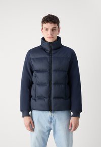 Ναυτικό μπλε μπουφάν τύπου puffer με ψηλό γιακά, φερμουάρ μπροστά, υφή στο σώμα και λεία μανίκια. Διαθέτει επενδεδυμένα τμήματα και ριμπ μανσέτες.