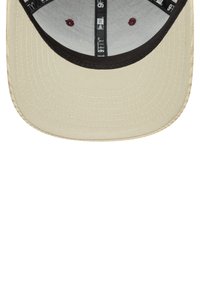 Cappellino da baseball beige con visiera piatta, sottosquadro nera e tessuto testurizzato. Presenta un logo discreto e un branding interno.