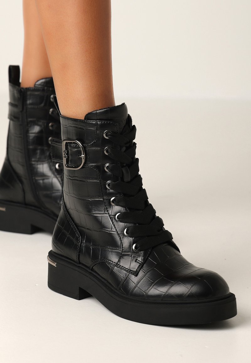 Černé kotníkové boty z umělé kůže s krokodýlí strukturou, šněrování vpředu a bočním detaily v podobě přezky. Masivní podrážka s mírným podpatkem.