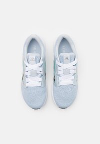 Baskets de sport bleu clair avec une tige en tricot texturé, des lacets blancs et des accents noirs et pastel, portant le logo Adidas et le texte "PRIMEGREEN".