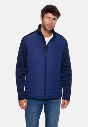 Chaqueta azul marino con parte delantera acolchada y acolchada y mangas sólidas, con cuello alto y cierre de cremallera con un logo en el pecho.