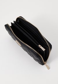 Portafoglio in pelle trapuntata nera con zip dorata, slot per carte multiple e scomparti divisi per l'organizzazione. Finitura testurizzata.