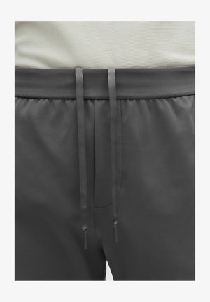 Pelēkas atlētiskās šortēs ar teksturētu audumu, kas aprīkoti ar aukliņu jostu ar saskaņotām galiņiem un smalku rakstu visā virsmā.