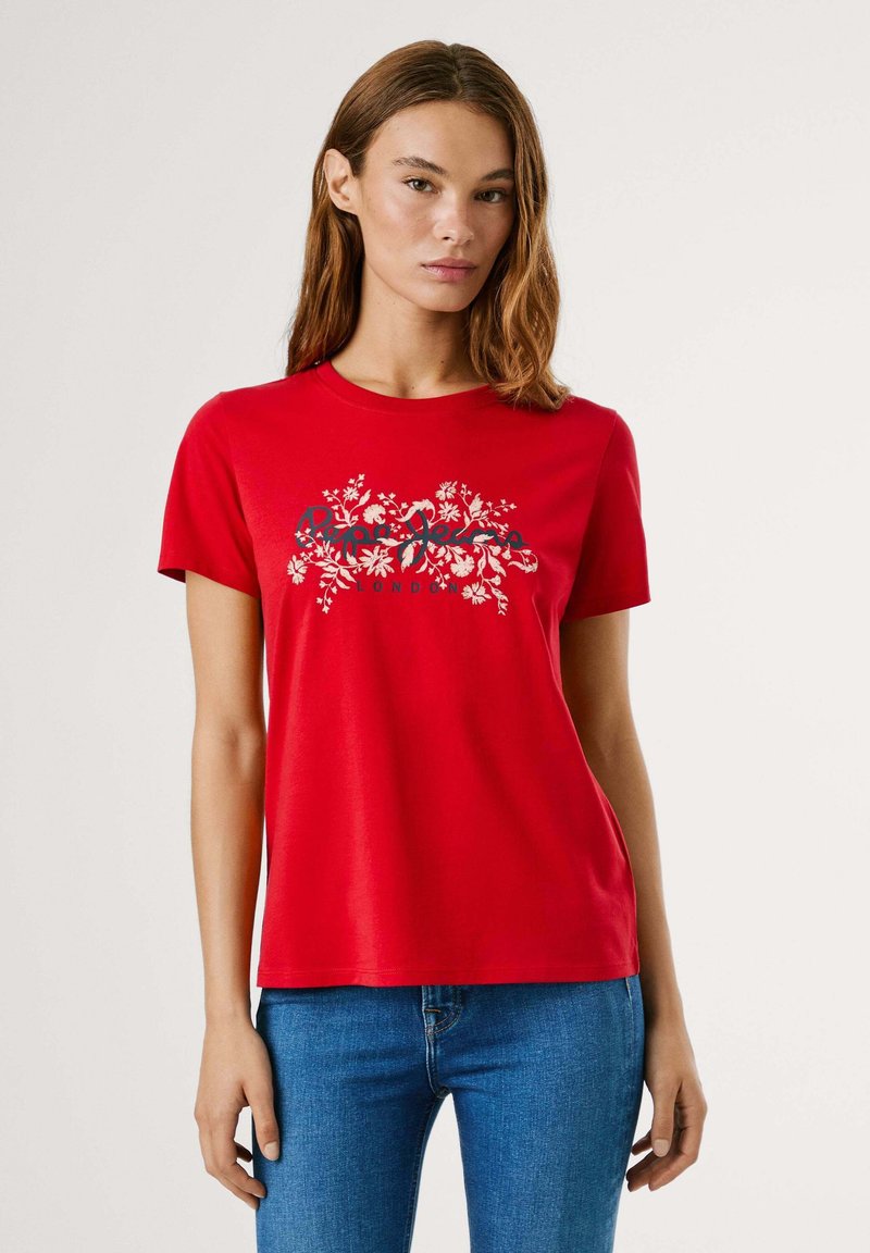 T-shirt rouge à manches courtes en coton, avec un imprimé graphique floral en blanc et noir. Encolure ronde et coupe régulière.
